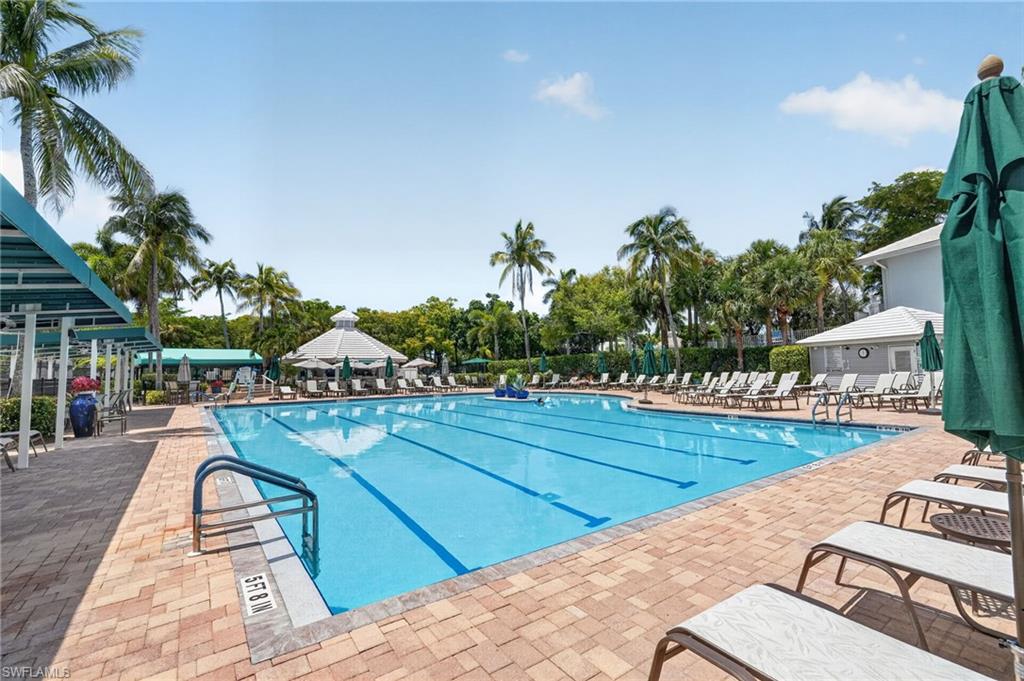 Expansive outdoor swimming pool with lane markers, paver surround, and multiple lounge chairs.