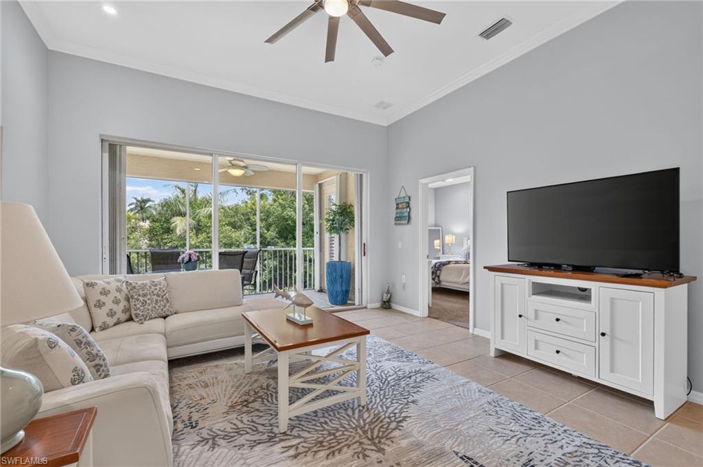 Vaulted ceiling, tile flooring, built-in ceiling fan, and sliding glass doors opening to an outdoor balcony.