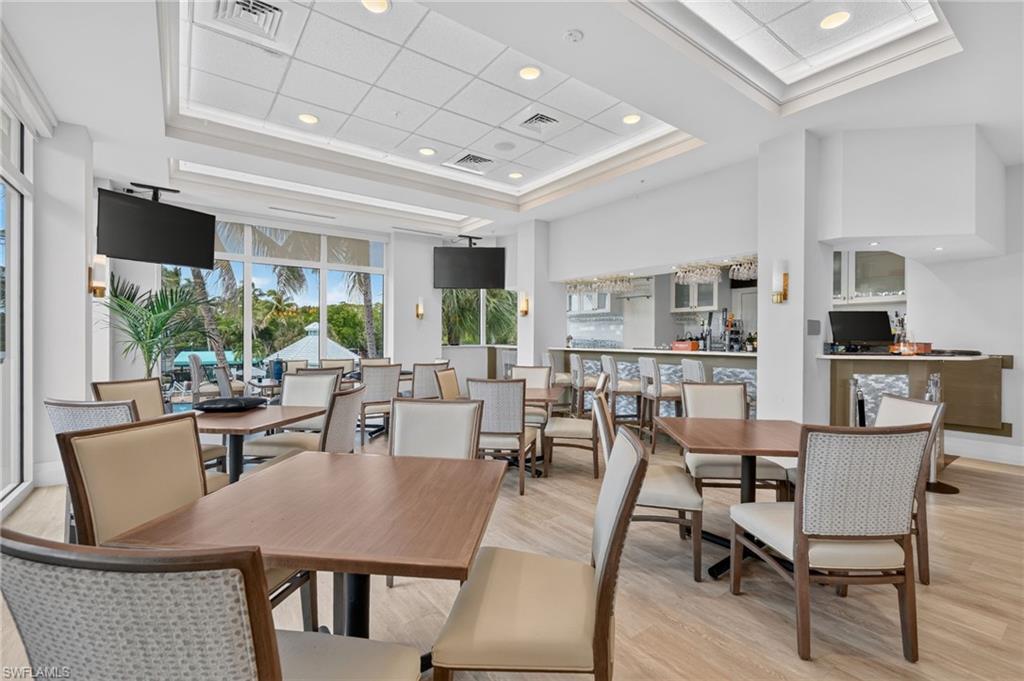 Open-concept dining area with wood-finish flooring, a tray ceiling, and recessed lighting