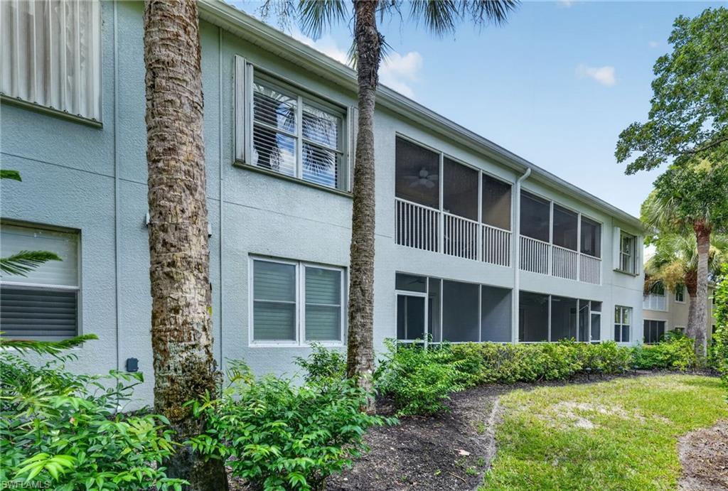 Stucco exterior with multiple screened balconies and patios, surrounded by mature palm trees and established landscaping
