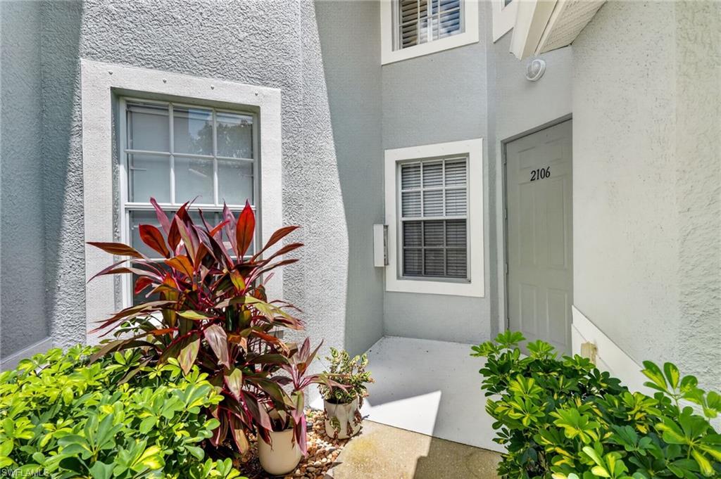 Stucco exterior with contrasting trim, multiple paneled windows, and established landscaping