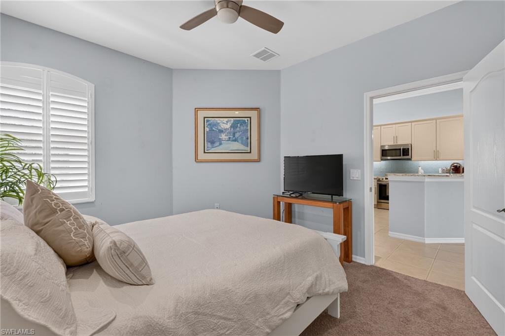 Recessed window with plantation shutters, ceiling fan, and carpeted flooring.