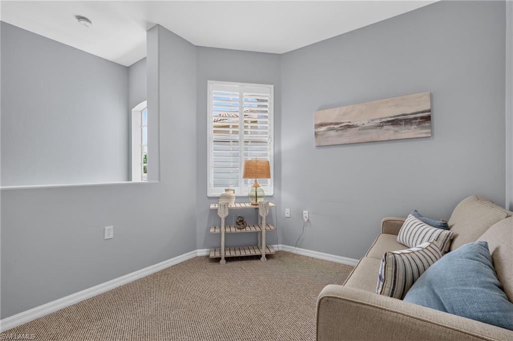 Loft area featuring neutral wall paint, carpet flooring, a window with white shutters, and a half-wall partition