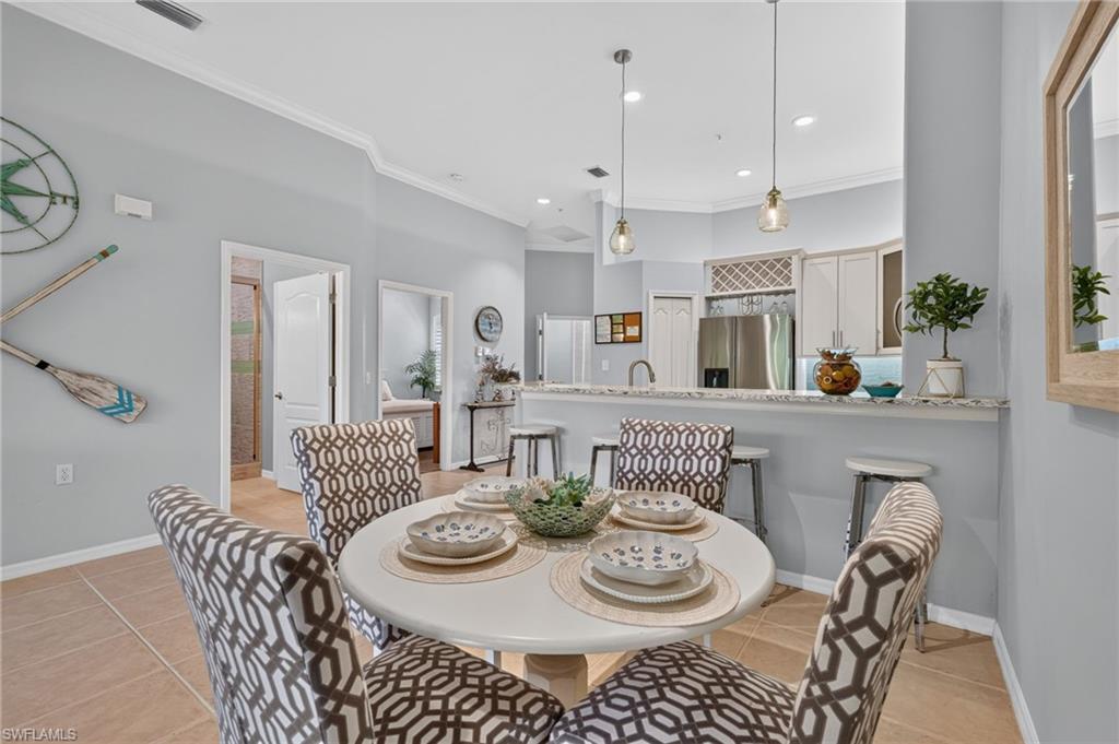 Open-concept kitchen and dining area featuring light-toned cabinetry, stainless steel appliances, and a breakfast bar with pendant lighting