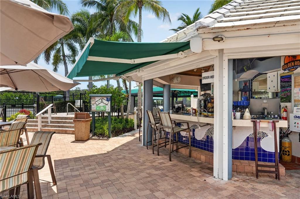 Outdoor bar area with a white tile roof, green retractable awning, and a tiled bar front.