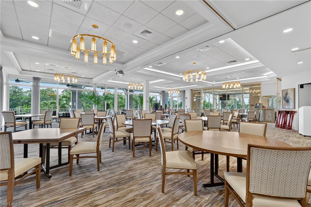 Spacious event hall featuring multiple brass chandeliers, recessed lighting, expansive window walls, and patterned carpeting.