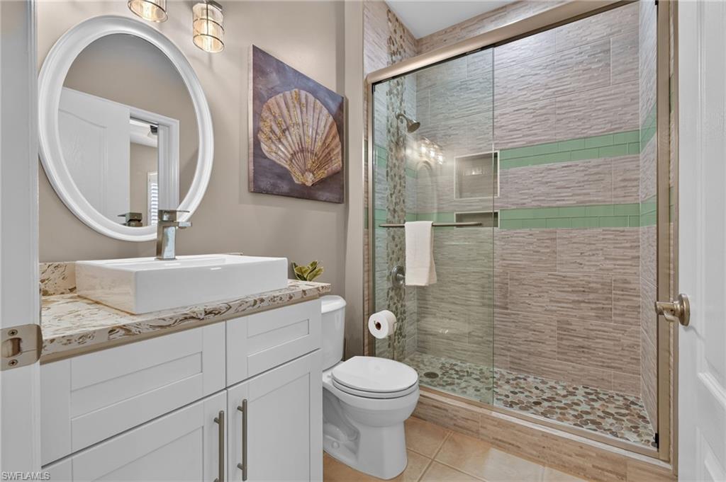 White shaker vanity with stone countertop, vessel sink, and chrome faucet.