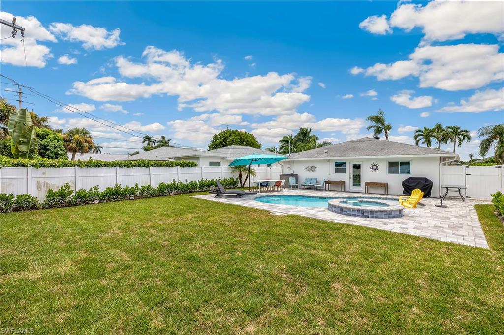 Back of house featuring a patio, a swimming pool with hot tub, and a lawn