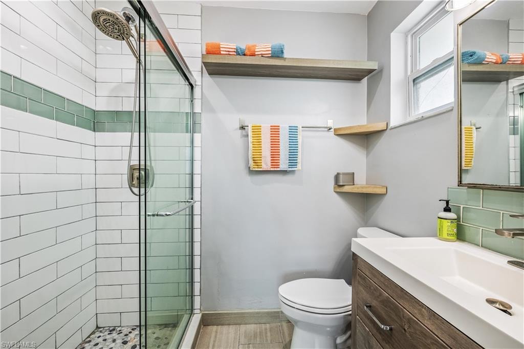 Bathroom with a shower with door, toilet, and vanity