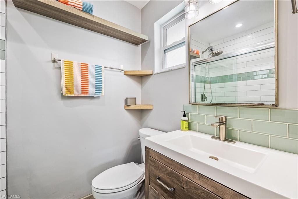 Bathroom with decorative backsplash, toilet, and vanity