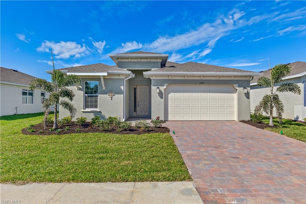 Model - Contemporary exterior with stucco finish, a two-car garage, paver driveway, and landscaped front yard