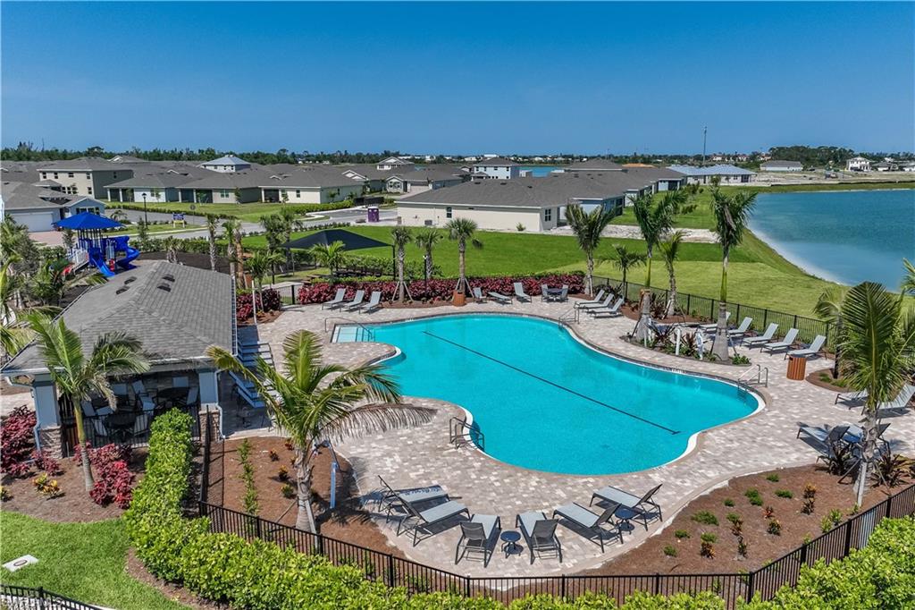 Swimming pool with paved surround, adjacent to a structured cabana, and a recreational play area
