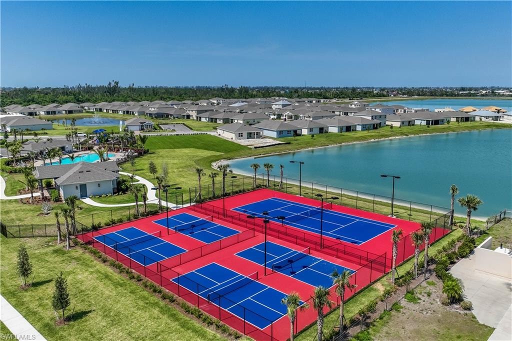 Recreational courts with blue playing surfaces and red surrounds, surrounded by a black perimeter fence
