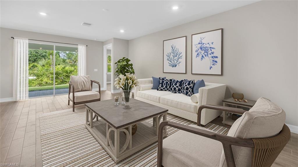 This image is virtually staged. Living room with light wood-style floors and recessed lighting