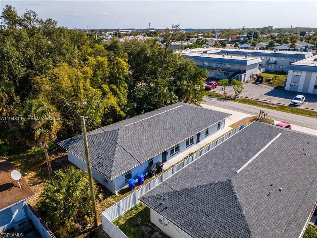 Pitched shingle roofing, light blue exterior siding, white perimeter fencing, and surrounding mature trees