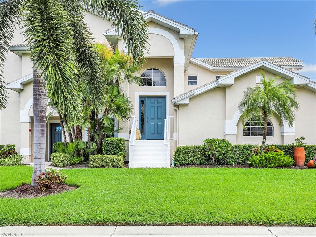 Stucco exterior with arched architectural details, white trim, and a teal entry door