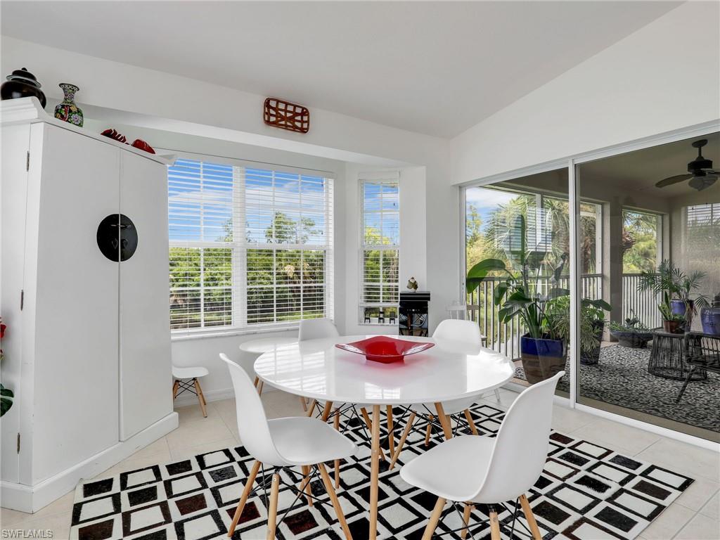 Bay window with horizontal blinds, built-in storage cabinet, tile flooring, and sliding glass doors leading to a screened lanai with a ceiling fan