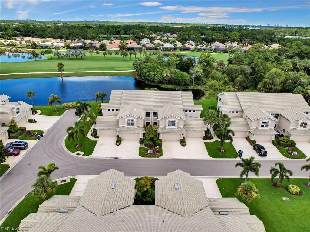 Aerial perspective featuring multiple properties with attached garages, surrounded by mature trees and manicured lawns