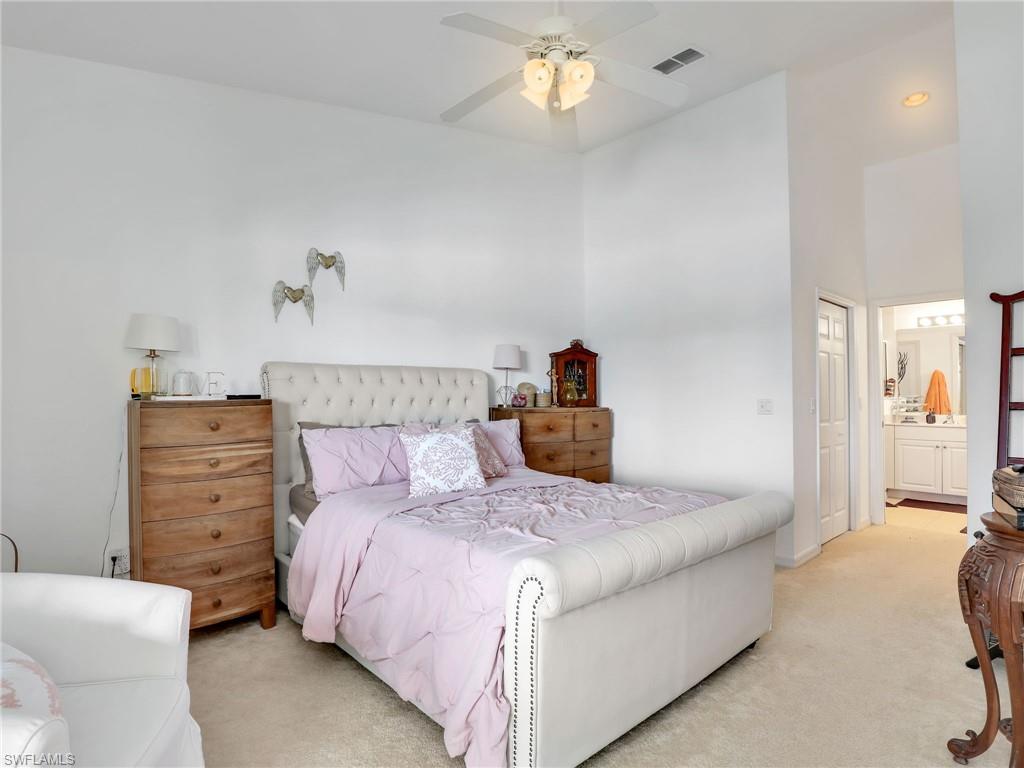 Vaulted ceiling, ceiling fan, recessed lighting, carpet flooring, and an attached bathroom with a double vanity