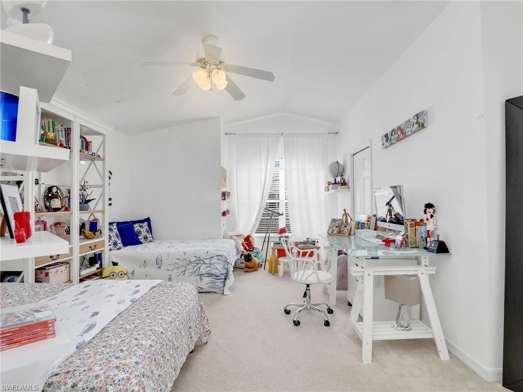Interior space featuring carpet flooring, built-in shelving, a ceiling fan with integrated lighting, and a window with blinds