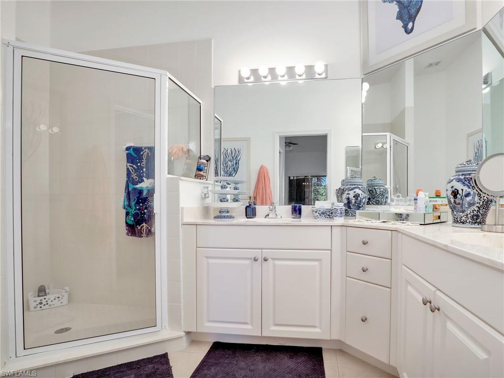 Walk-in shower with clear glass enclosure and white tile surround