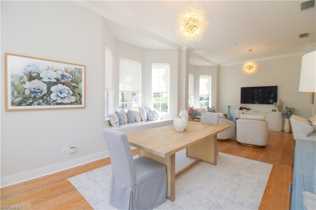 Dining area featuring ornamental molding, light wood-type flooring, visible vents, and an inviting chandelier