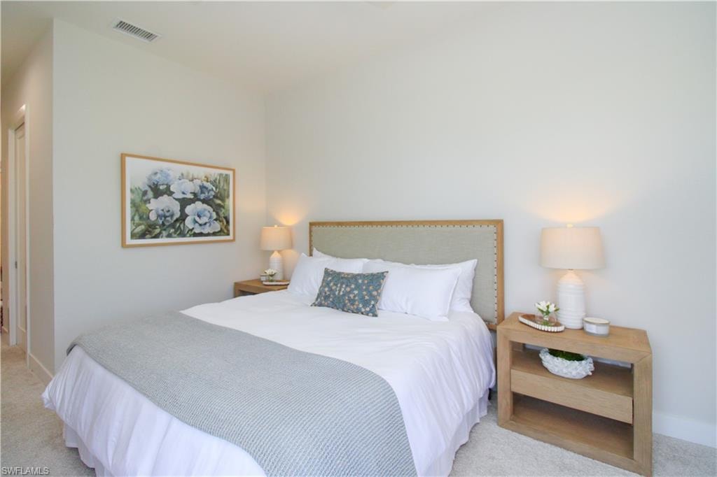 Bedroom featuring light colored carpet and visible vents