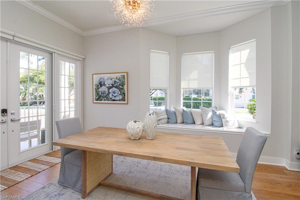 Dining room with light wood finished floors, plenty of natural light, a chandelier, and crown molding