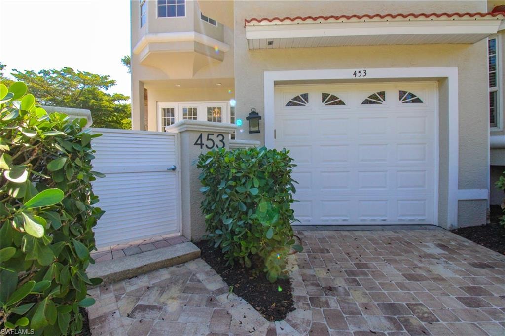 Property entrance with a garage, decorative driveway, and stucco siding