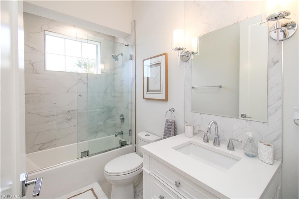 Bathroom with toilet, tasteful backsplash, combined bath / shower with glass door, and vanity