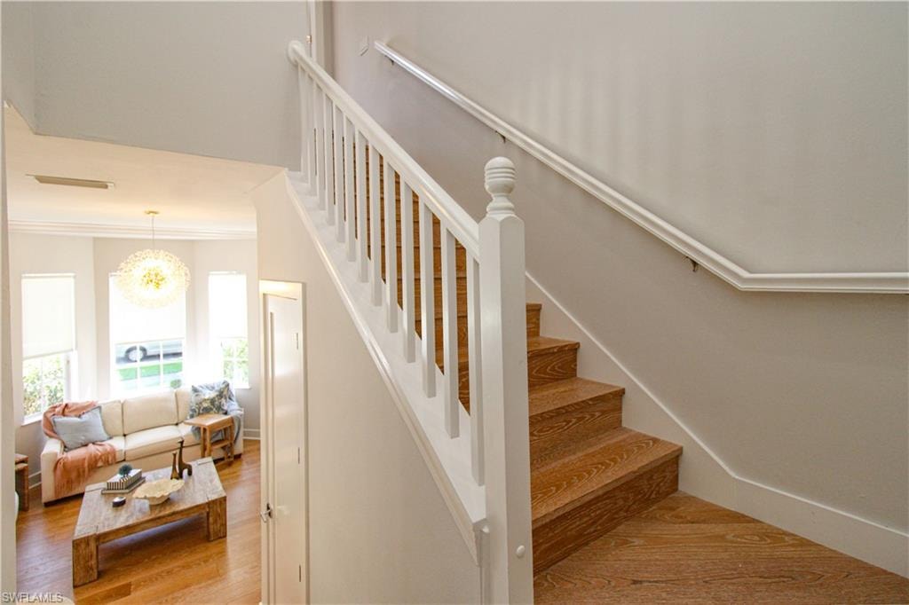 Stairs featuring an inviting chandelier, baseboards, and wood finished floors