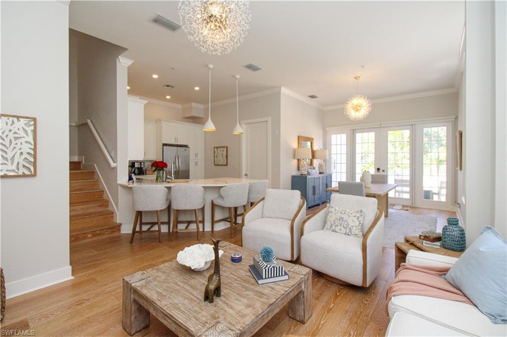 Living room with a chandelier, light wood-type flooring, stairs, and visible vents
