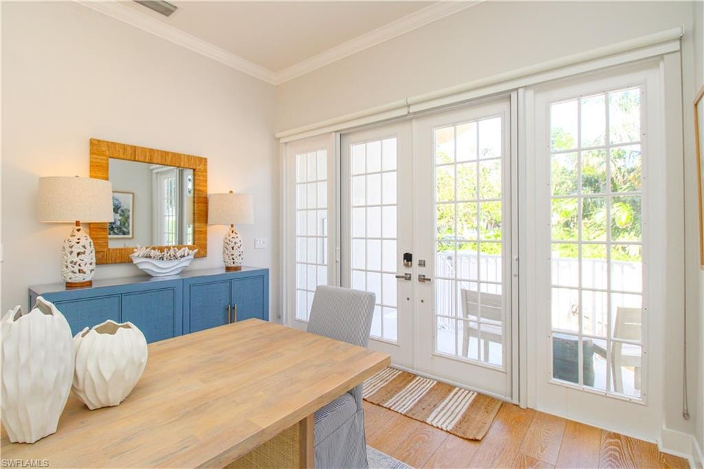 Dining area featuring visible vents, ornamental molding, wood finished floors, and french doors