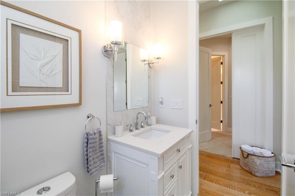 Bathroom featuring toilet, wood finished floors, and vanity