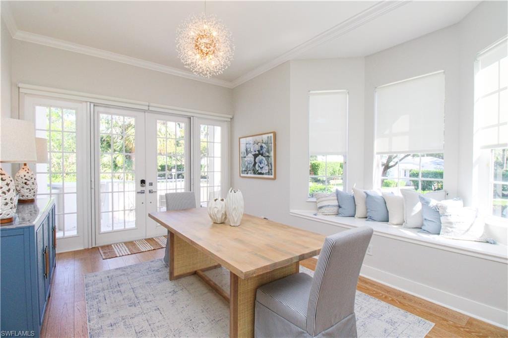Dining space featuring light wood finished floors, ornamental molding, a chandelier, and french doors