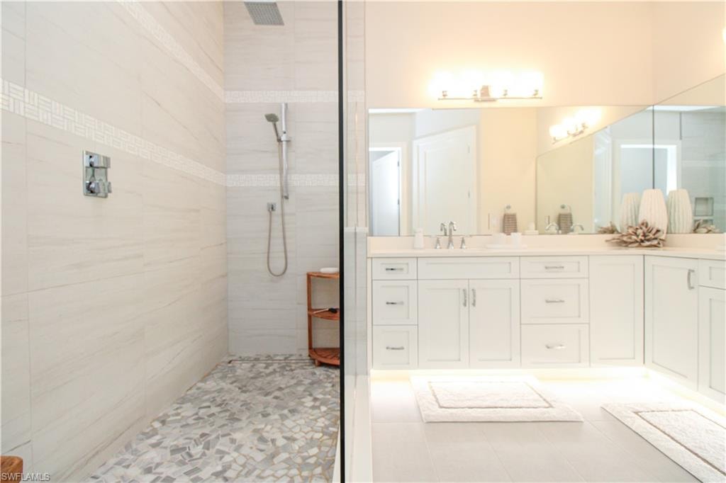 Full bathroom with double vanity, visible vents, a sink, tile patterned flooring, and walk in shower