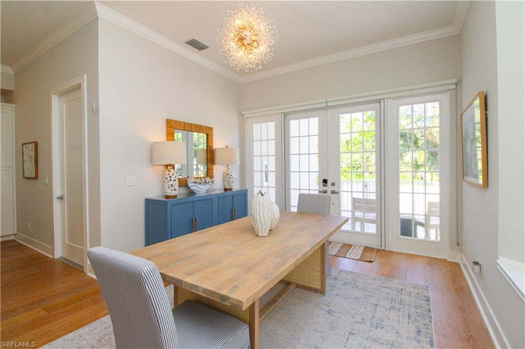 Dining space featuring light wood-style floors, visible vents, crown molding, and an inviting chandelier