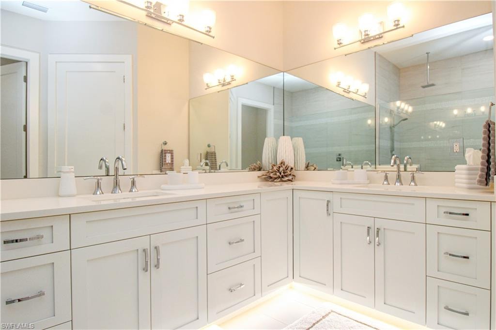 Bathroom featuring double vanity, a shower stall, visible vents, and a sink