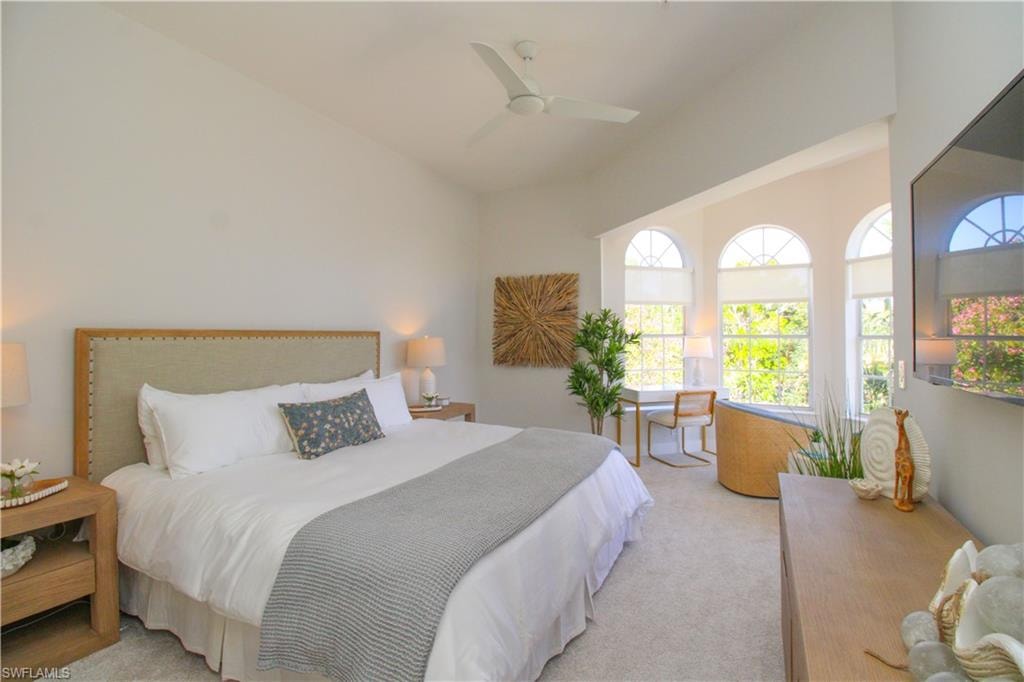 Bedroom with light carpet, vaulted ceiling, and a ceiling fan