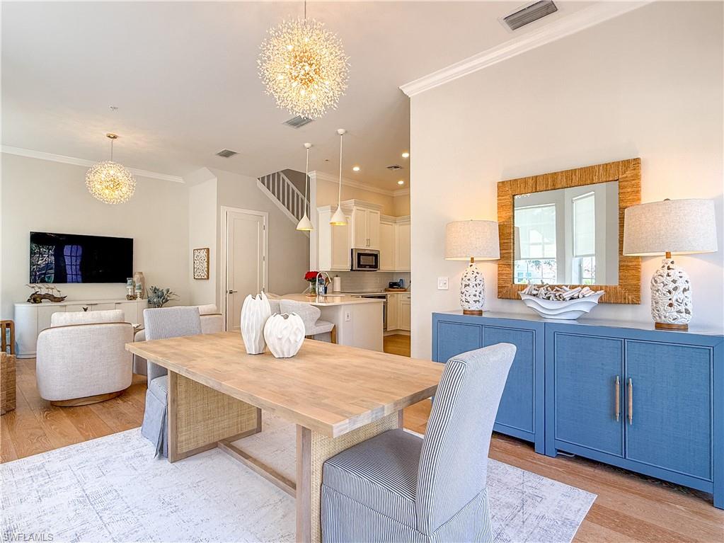 Dining room with light wood finished floors, visible vents, and a chandelier