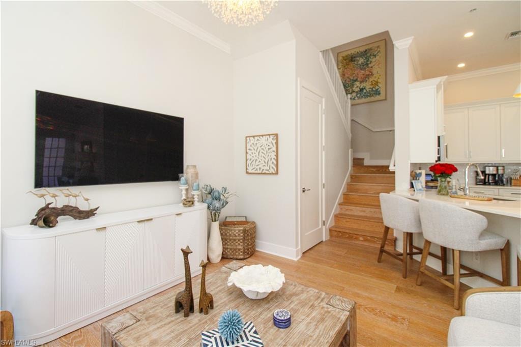 Living area with stairs, recessed lighting, light wood-style flooring, and crown molding