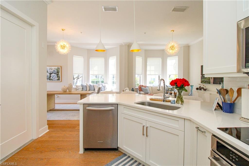 Kitchen featuring a sink, stainless steel oven, open floor plan, light countertops, and hanging light fixtures