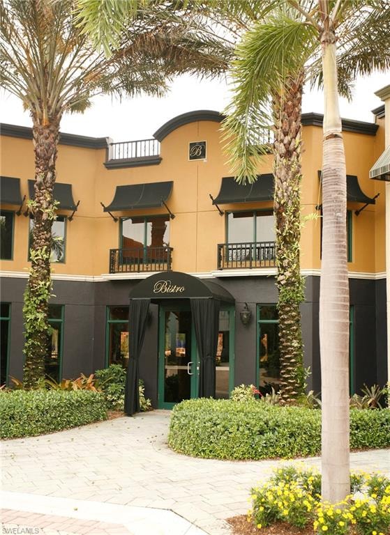 Building facade with a curved parapet, black awnings, and decorative railings