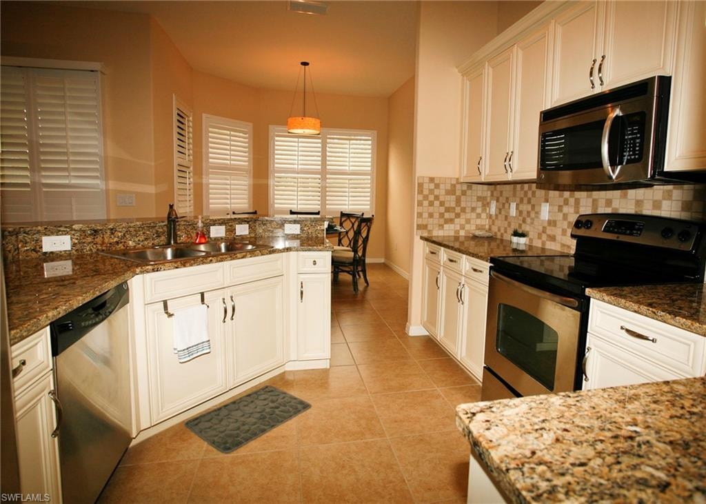 Kitchen with white cabinetry, stainless steel appliances, speckled countertops, and a tiled backsplash