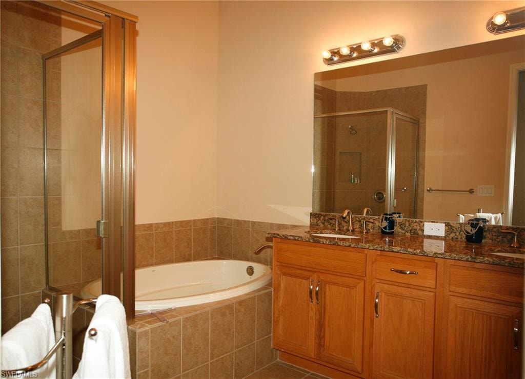 Dual vanity with wood-finish cabinetry, stone countertop, and two undermount sinks