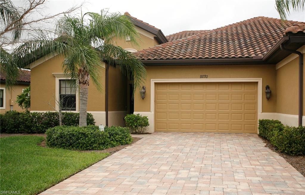 Mediterranean-style architecture with a terracotta tile roof, stucco exterior, and an integrated garage