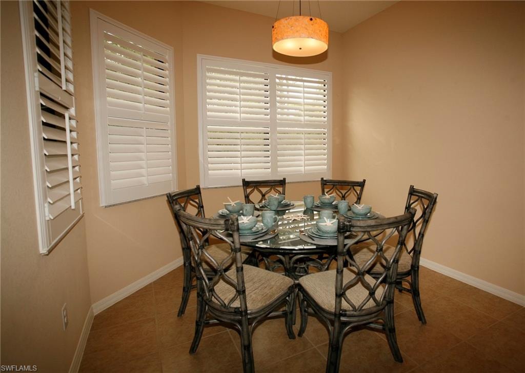 Tile flooring with white baseboards, textured drum pendant light, and multiple windows with plantation shutters