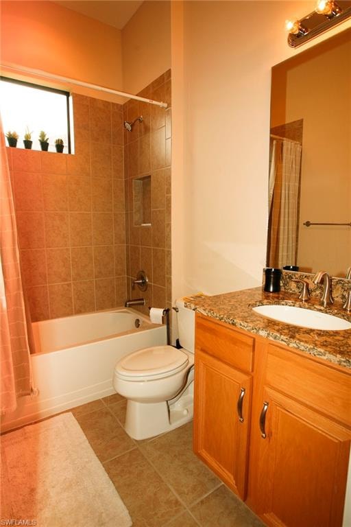 Tiled flooring with a matching tiled shower surround, recessed shower niche, wood-finish vanity with a granite-style countertop, and an integrated oval sink