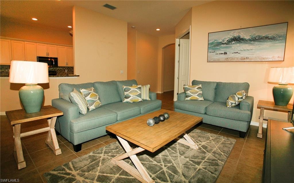 Open-concept living area featuring tile flooring, a half-wall partition, and vaulted ceilings