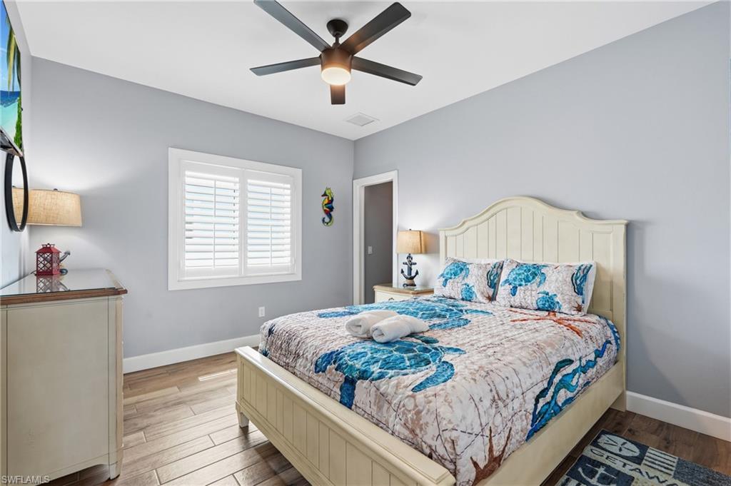 Wood-finish flooring, ceiling fan with integrated lighting, window with plantation shutters, and light blue walls - Virtually Edited Image